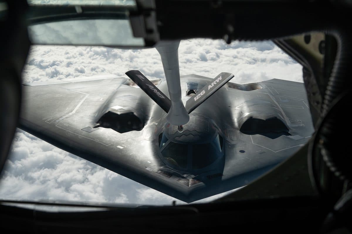 B-2 Spirit stealth bomber seen from above during aerial refueling, showcasing its distinctive flying wing design