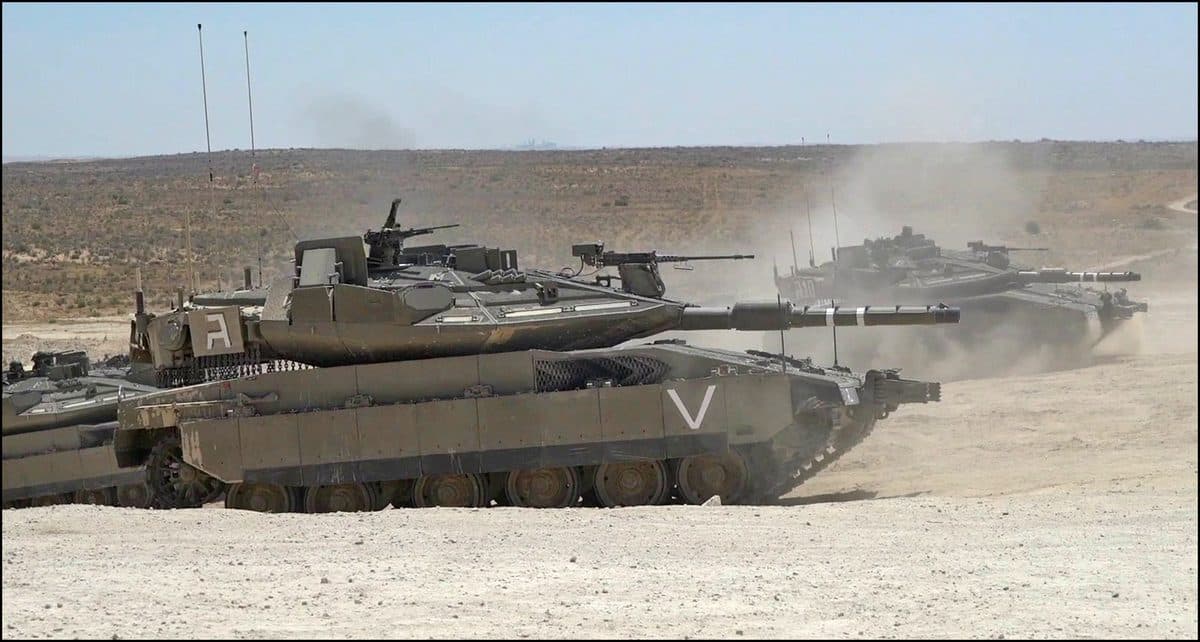 Merkava Mk 4 main battle tank moving through desert terrain showing its distinctive sloped turret and front-mounted engine