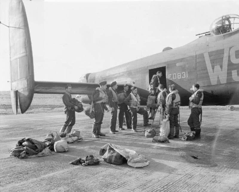 Lancaster bomber crew gathering gear beside their aircraft, serial ED831, before a mission