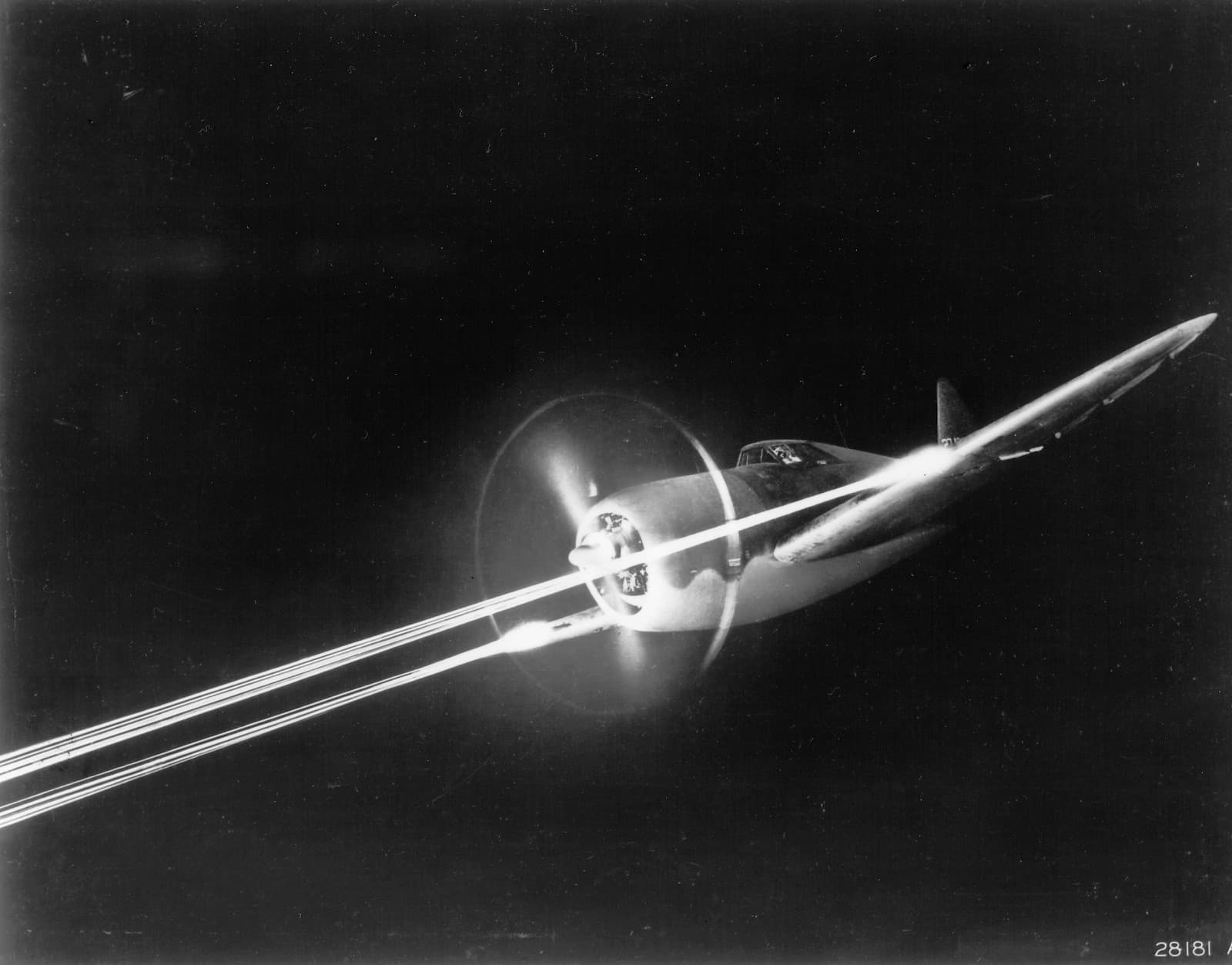 P-47 Thunderbolt firing its eight .50 caliber machine guns with tracer rounds visible during a night gunnery exercise