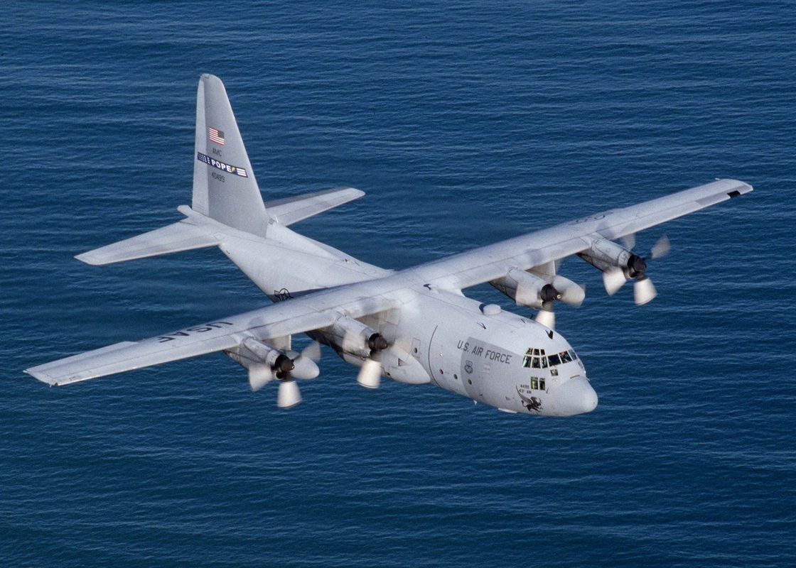 C-130 Hercules performing a tactical landing on a dirt airstrip