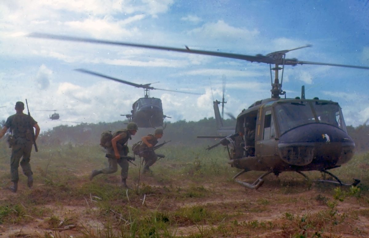 UH-1 Huey helicopters in formation over Vietnam jungle canopy