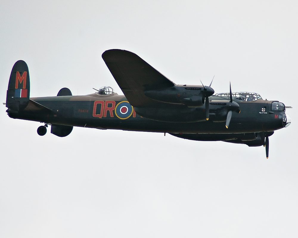Avro Lancaster heavy bomber silhouetted against searchlights during night raid