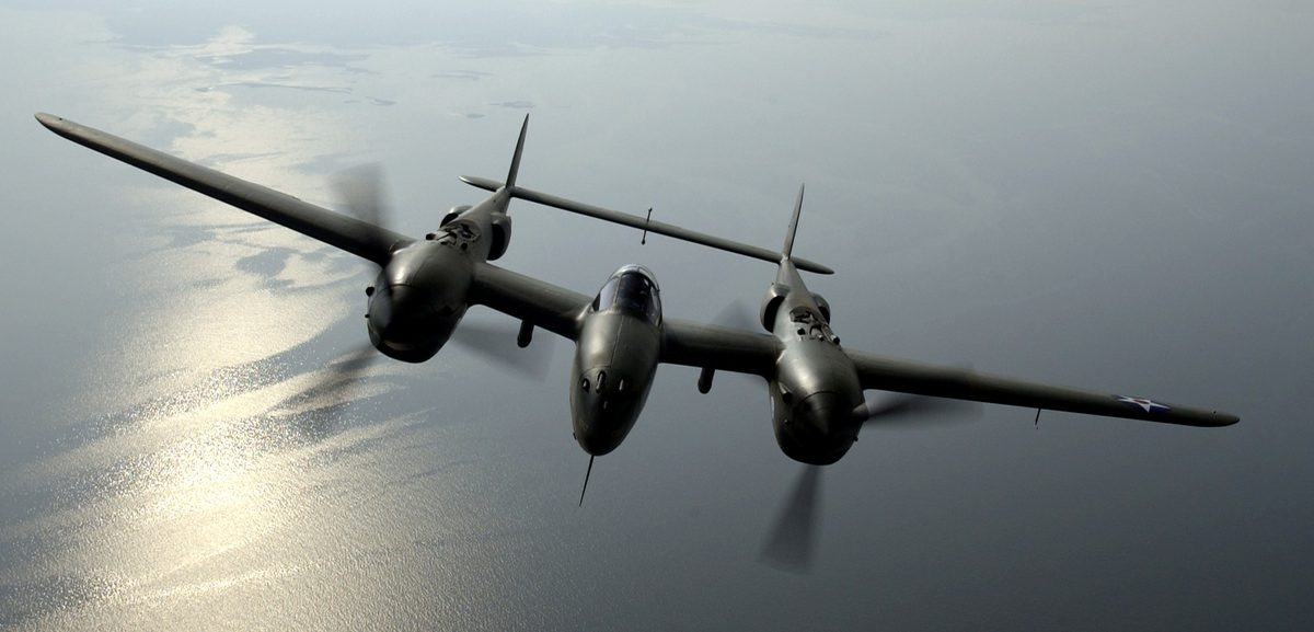P-38 Lightning with distinctive twin-boom design flying over Pacific islands