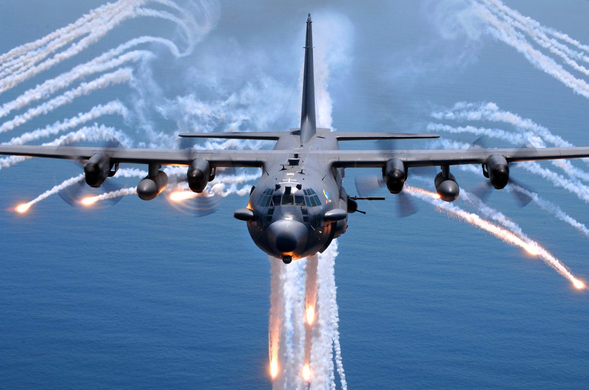 AC-130 gunship firing at night with tracer rounds visible in a pylon turn