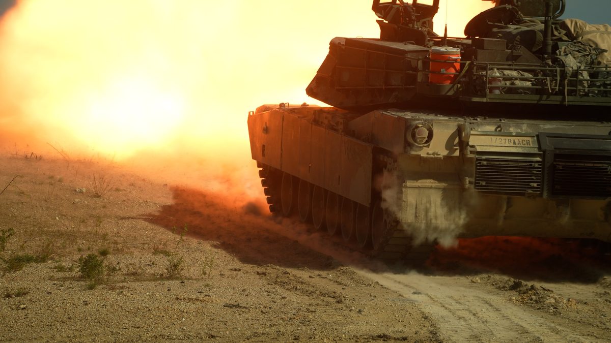 M1 Abrams main battle tank firing its 120mm smoothbore gun with a large muzzle blast