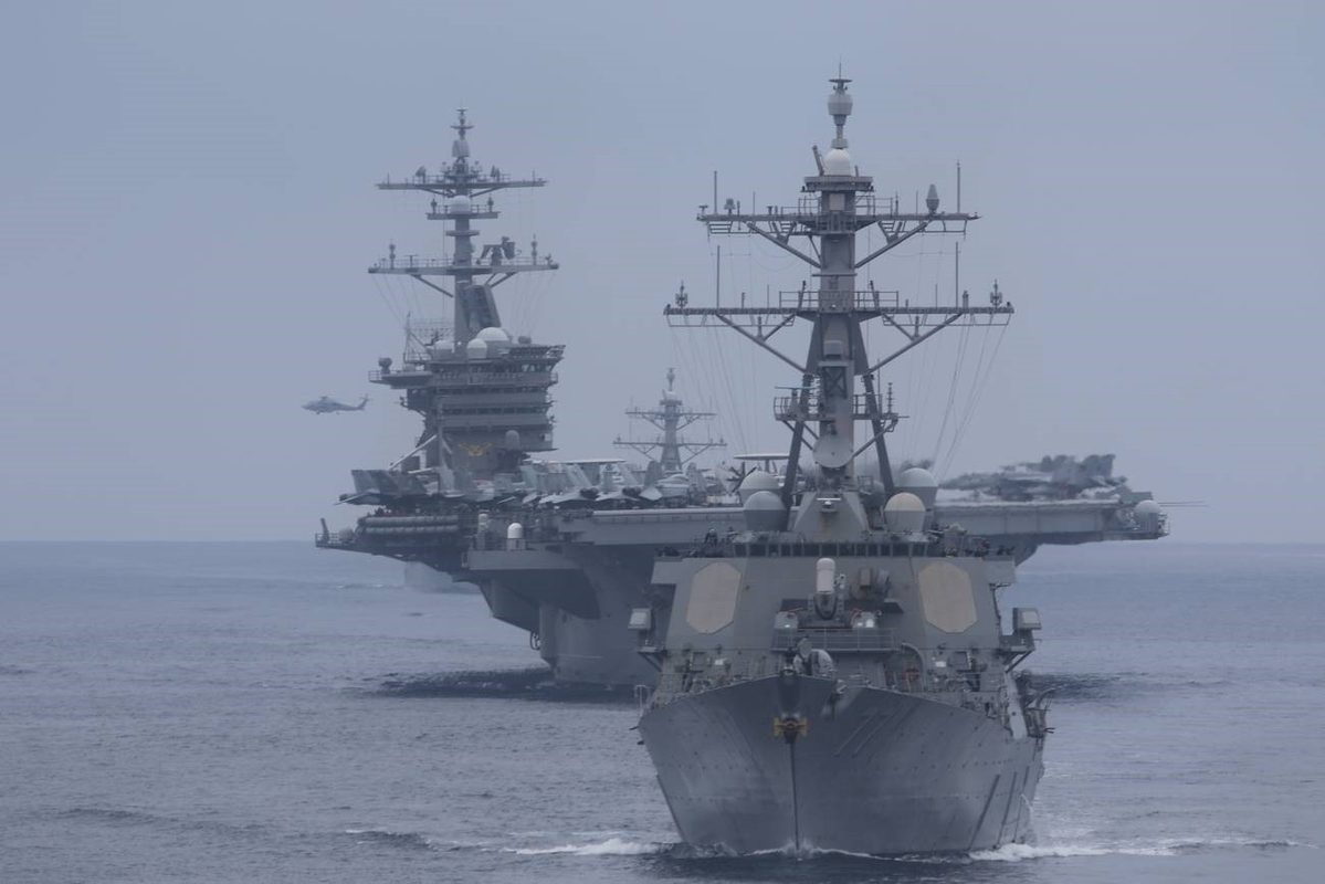 Aerial view of carrier strike group ships steaming in formation across open ocean