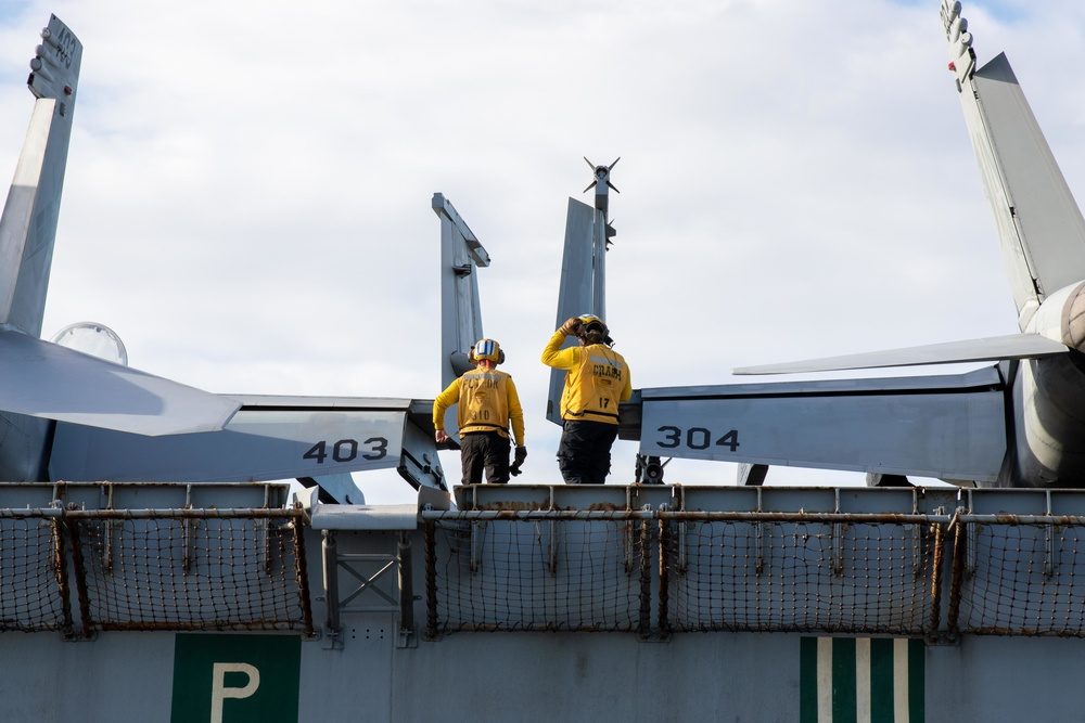 Aircraft carrier flight deck showing the angled landing area with F/A-18s parked on deck