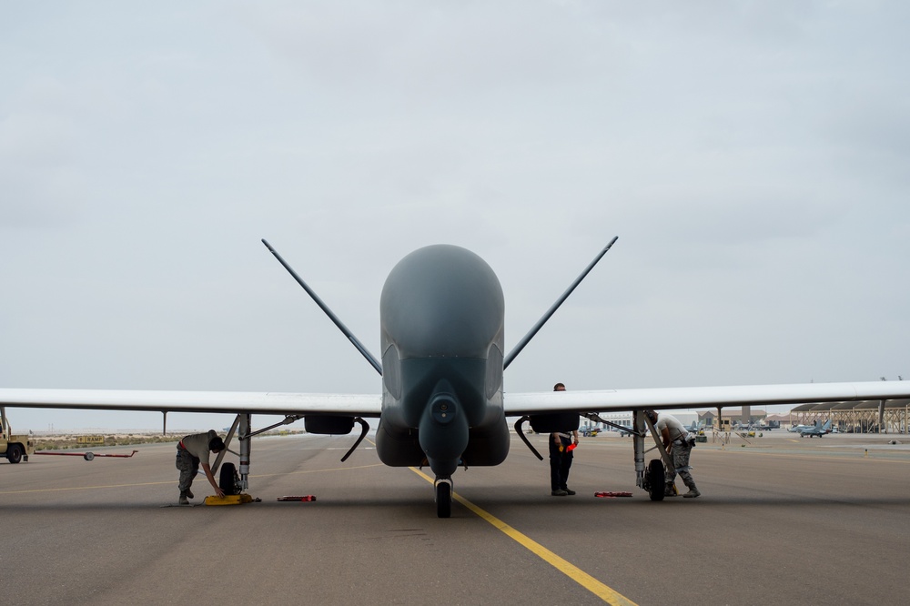 A maintenance crew secures an RQ-4 Global Hawk on a runway after completing a sortie in support of Operation Inherent Resolve