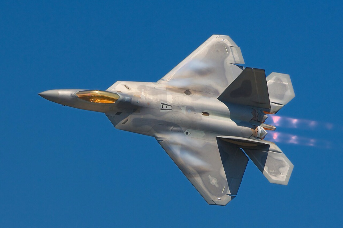 F-22 Raptor in flight during operations, showing the aircraft from a rear quarter angle with its twin engines and stealth profile visible