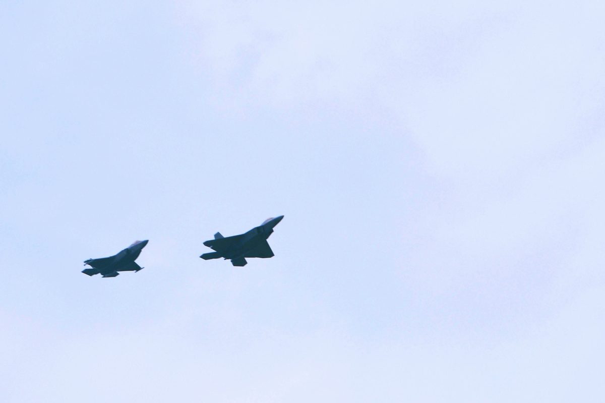 F-35 Lightning II and F-22 Raptor flying side by side over the flight line at Eglin Air Force Base, Florida