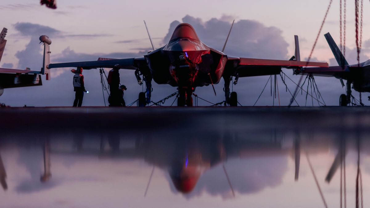 Sailors conducting maintenance on an F-35C Lightning II on the flight deck of the USS George Washington in the Pacific Ocean