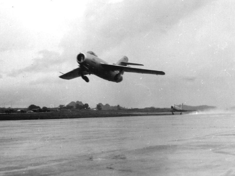 MiG-15 taking off with an F-86 Sabre visible in the background at a test facility