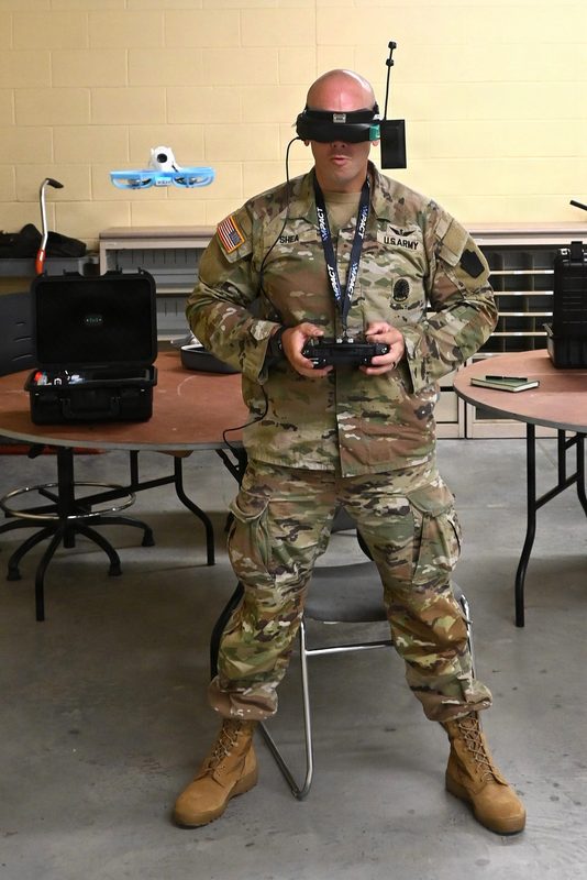 Close-up of a small FPV-style drone being prepared for flight during military exercises