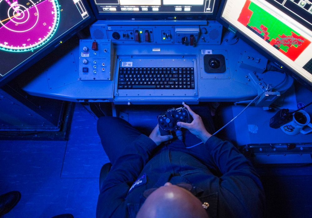 High-energy laser weapon system firing from a Navy destroyer at dusk