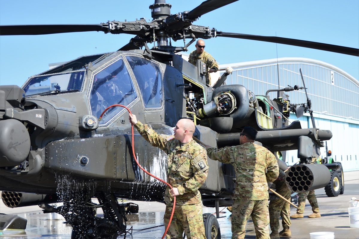 AH-64 Apache attack helicopter on a flight line with sensor dome and chain gun visible