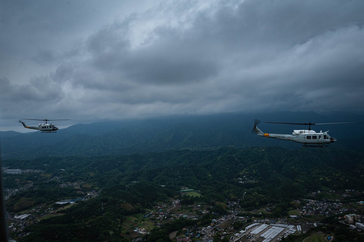 UH-1 Huey helicopters flying in formation over mountainous terrain