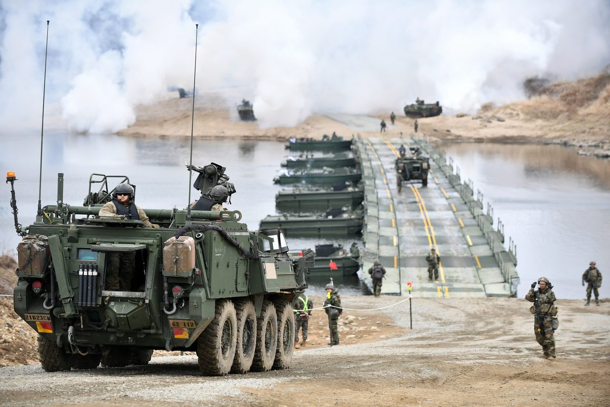 U.S. Army soldiers working to assemble pontoon bridge sections during a river crossing exercise