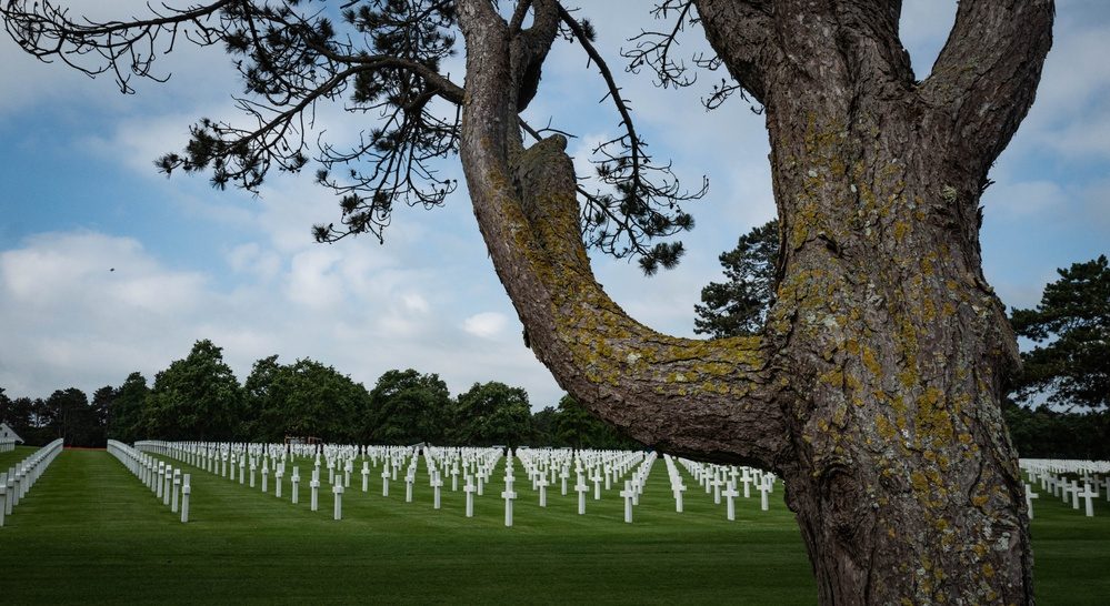Soldiers stand among white crosses at the Normandy American Cemetery in France