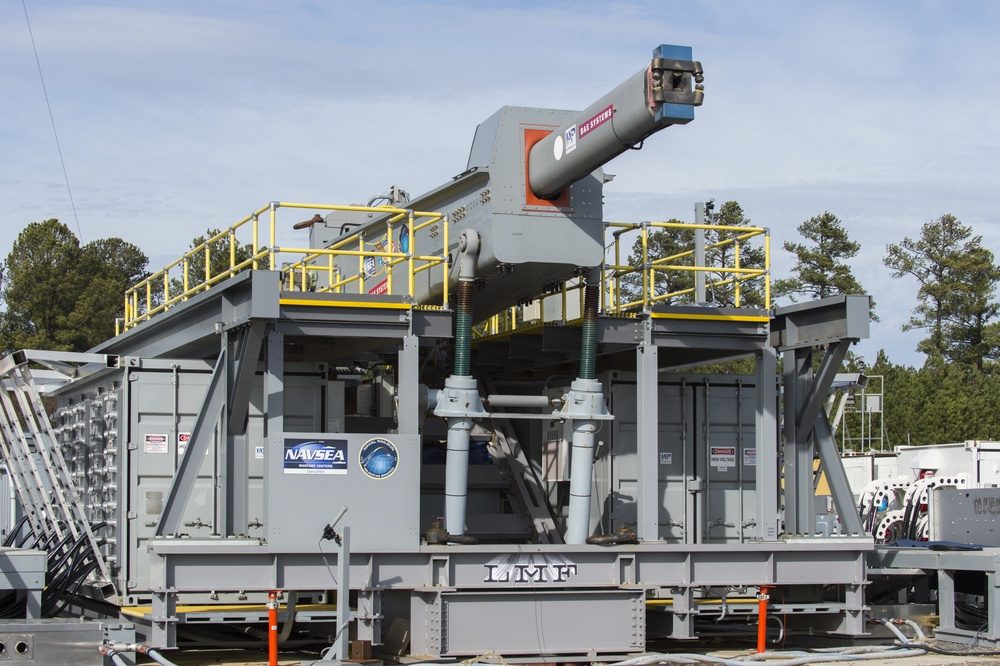 Close-up of electromagnetic railgun barrel rails showing severe erosion and pitting damage from electromagnetic forces and extreme heat