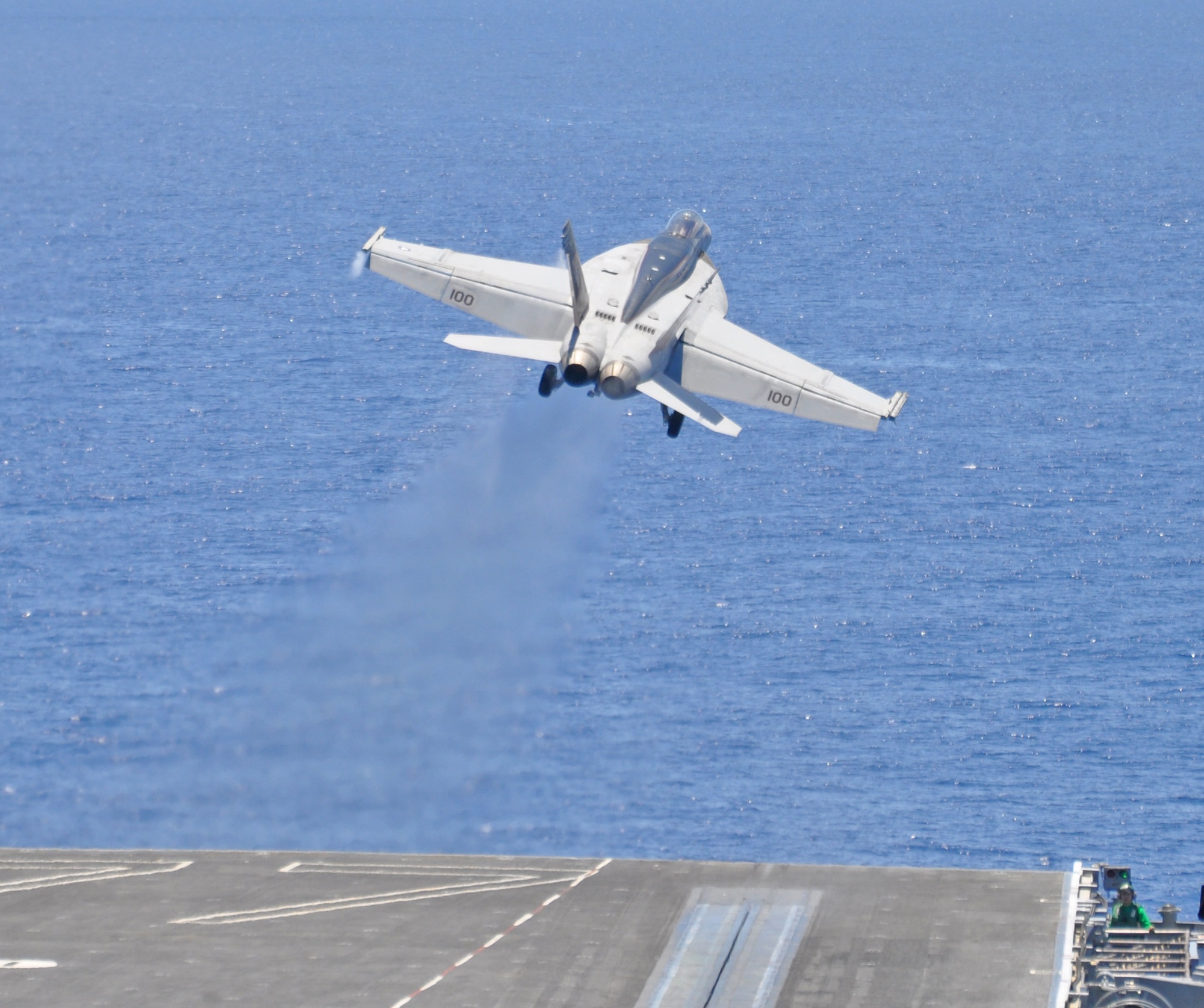 F/A-18E Super Hornet launching from an aircraft carrier flight deck with afterburner engaged