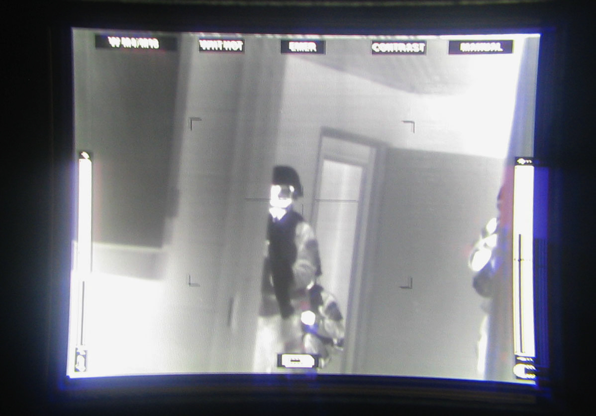 Thermal imaging view showing heat signatures of soldiers and vehicles during a military exercise