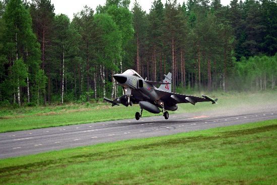 Saab Gripen taking off from a road runway strip with forest in the background